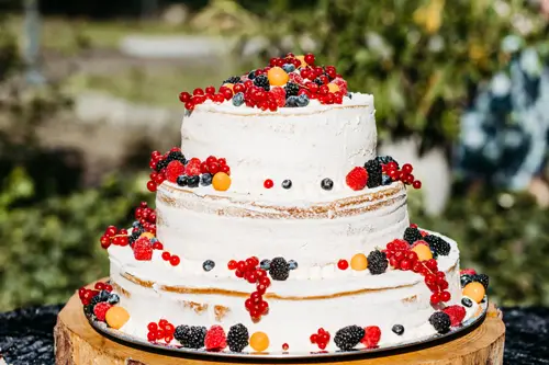 Eine dreistöckige Hochzeitstorte, die mit roten und schwarzen Beeren verziert ist.