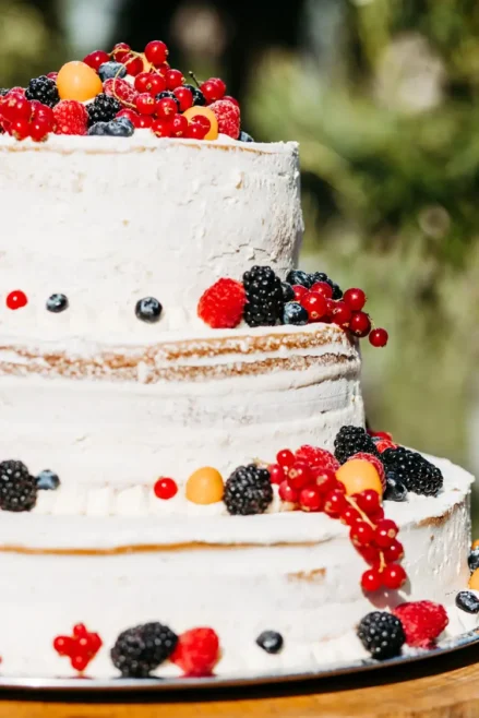 Eine dreistöckige Hochzeitstorte, die mit roten und schwarzen Beeren verziert ist.
