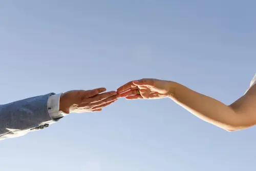 Zwei Hände strecken sich vor einem strahlend blauen Himmel nacheinander aus. Die linke Hand trägt ein Jackett, die rechte ist nackt. Es scheint, als hätte ein Hochzeitsfotograf in Marcolinis Welt diesen Moment eingefangen, in dem die Verbindung zur Kunst wird, kurz bevor ihre Berührung sie vollendet.
